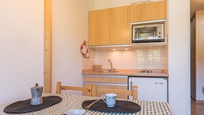 A compact kitchen with wooden cabinets, a microwave, and a sink. - Cozy studio 3 pers Montgenèvre, south balcony, 20m² (Montgenèvre)