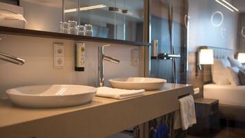 A modern bathroom with two sinks, a large mirror, and a visible shower area.