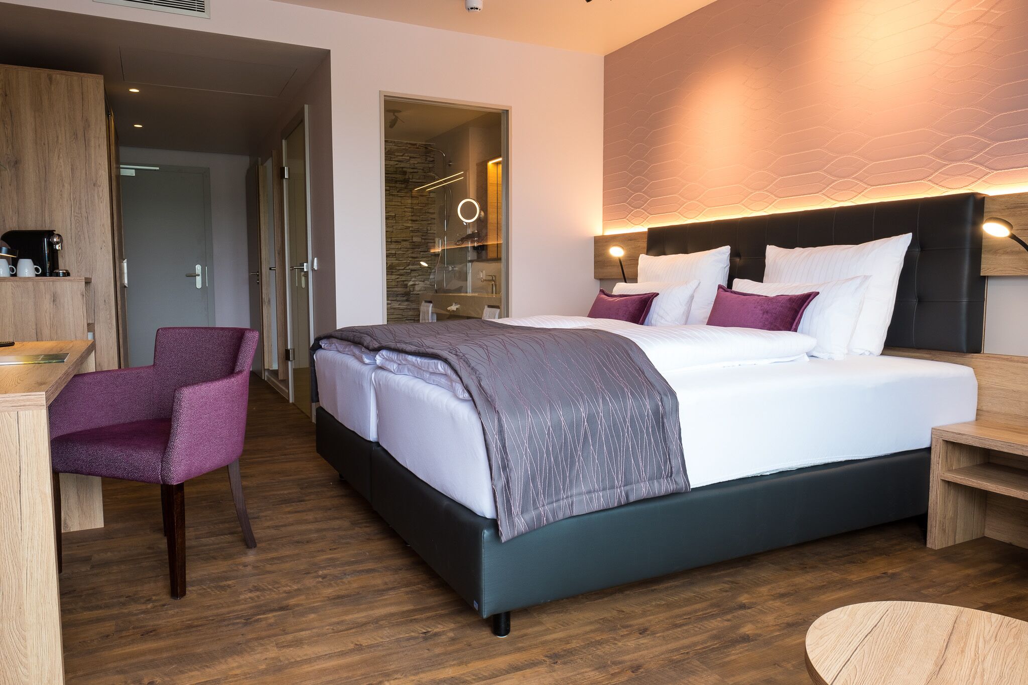 Une chambre d’hôtel moderne avec un grand lit, un bureau avec une chaise et une petite table ronde.