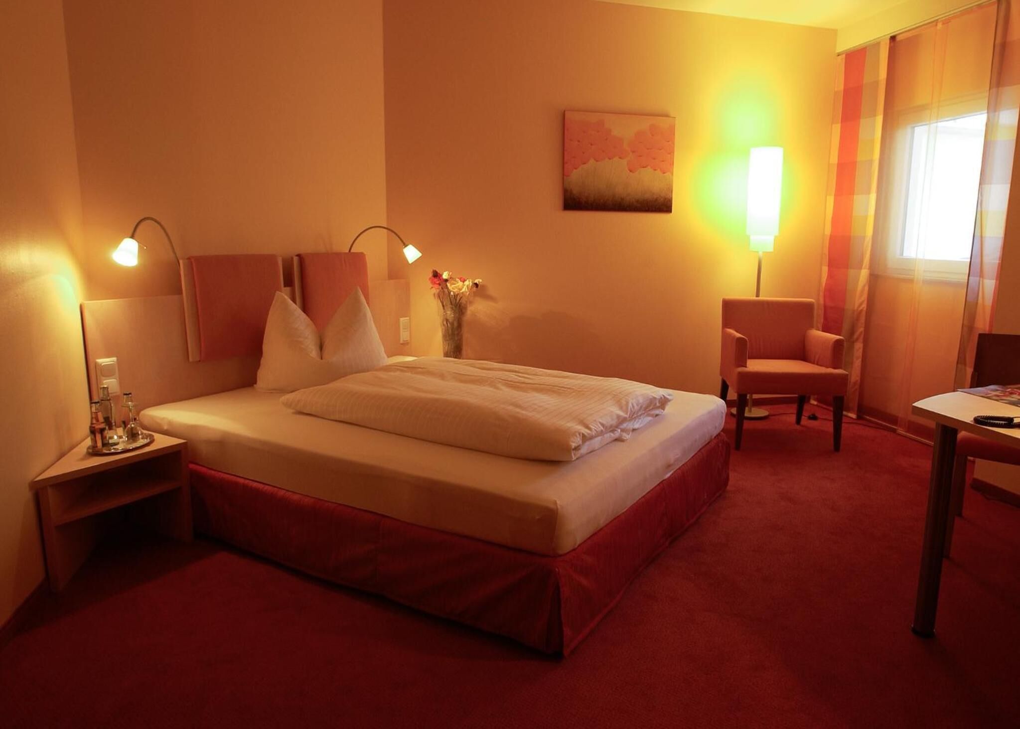 Une chambre d’hôtel comprenant un lit, des tables de chevet, une chaise, un bureau et une lampe.