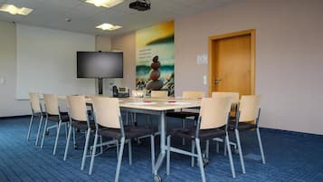A conference room with a large table, chairs, a projector, and a screen.
