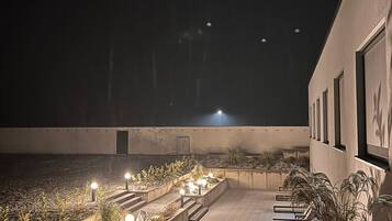 A nighttime outdoor area with a pathway, planters, and a building with windows.
