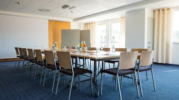 Una sala de conferencias con una larga mesa, sillas y un proyector.