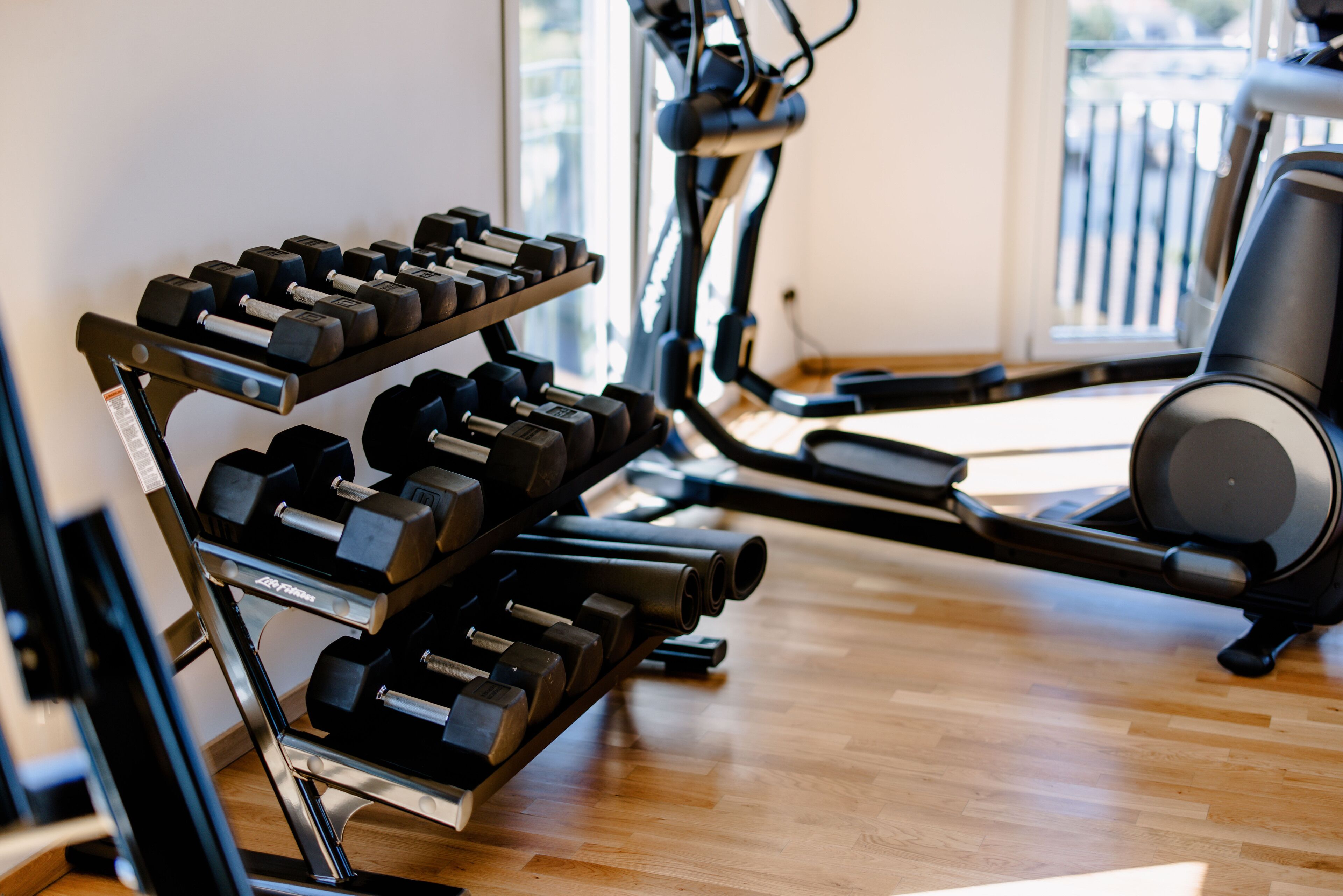 A gym with a rack of dumbbells, a stationary bike, and a treadmill.