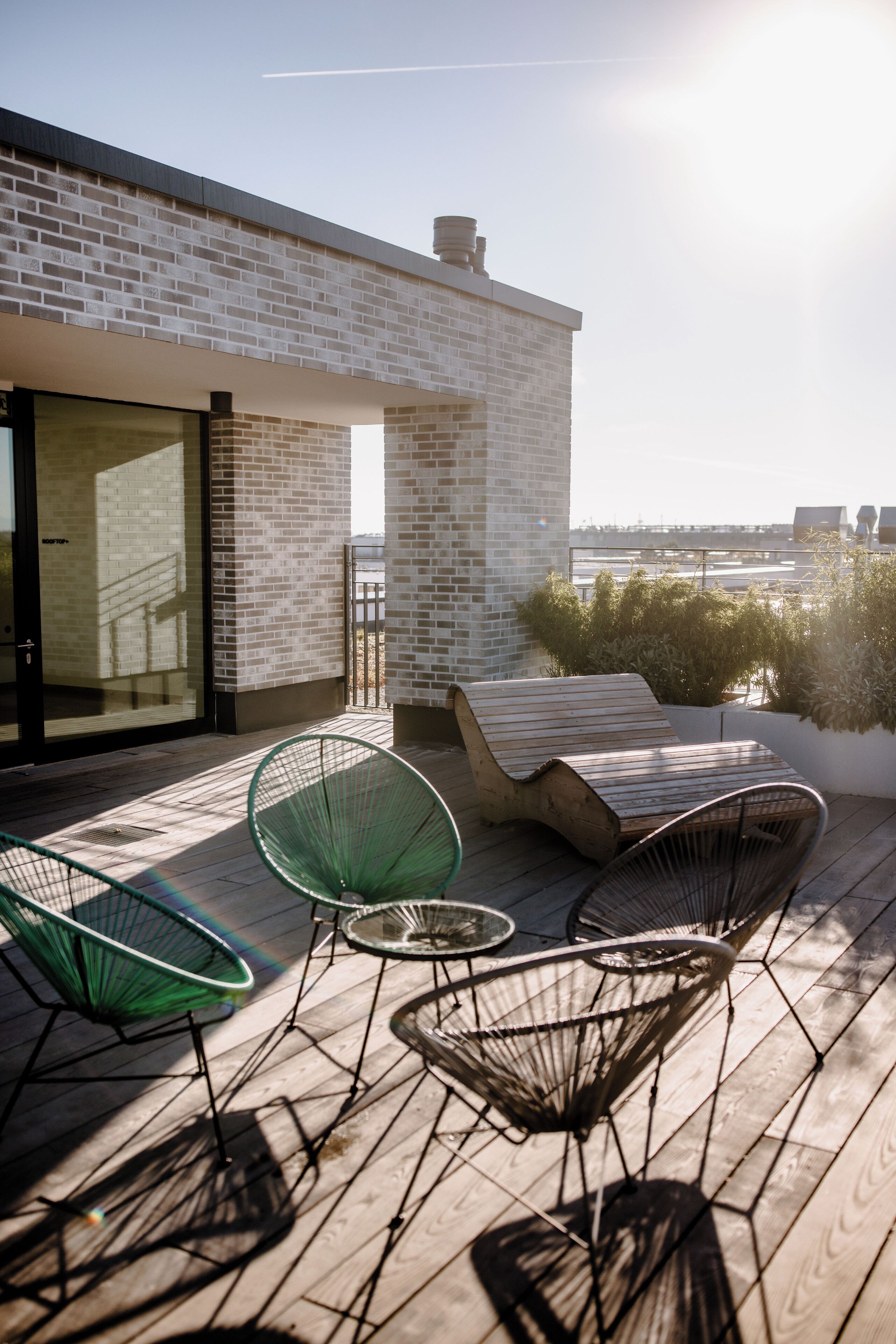 A rooftop terrace with a brick wall, a glass door, and a view of the city skyline.