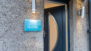 Ein Gebäudeeingang mit einem Schild mit der Aufschrift 'THE SHORE' und einer runden Glasschleuse.