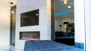 Ein modernes Wohnzimmer mit Steinwand, Flachbildfernseher, integriertem Kamin und einer blauen Sitzbank.