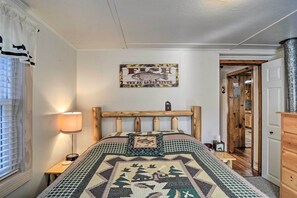 Een slaapkamer met een bed, een nachtkastje, een lamp, een bord aan de muur en een houten deur.