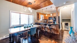 Une cuisine moderne avec des meubles en bois, un îlot central, des tabourets de bar et des luminaires suspendus.