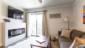 Una sala de estar moderna con chimenea, un sofá, una mesa de centro y un televisor montado en la pared.