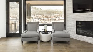 A modern living room with two upholstered chairs, a round coffee table, and a flat-screen TV mounted on the wall. - Stunning! Walk to lift - Beautiful pool complex (Park City)