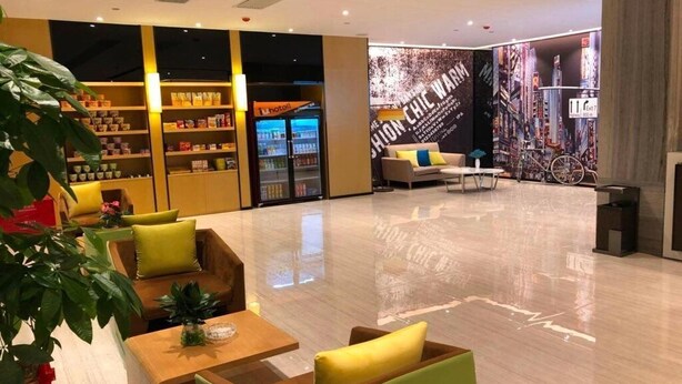 Un hall d’hôtel moderne, doté d’espaces de détente, d’un bar et d’une grande fresque représentant un paysage urbain.