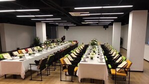 Une longue table à manger, agrémentée de chaises, de nappes blanches et de centres de table.