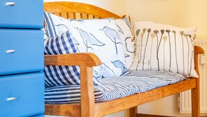 A wooden bench with striped cushions and a dolphin pattern pillow, positioned next to blue storage units. - Waldstr. 32 Whg. Wa32-04 - Wa32-04 (Kühlungsborn)