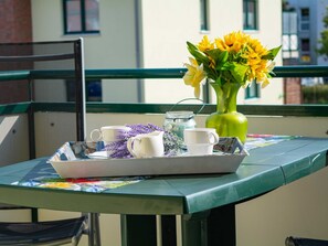 Ett bord med ett bricka som innehåller en vit kanna, en vit kopp och en vas med gula blommor.