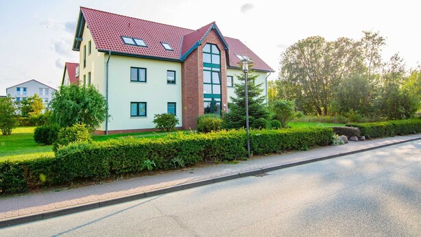 A two-story residential building with a red-tiled roof, large windows, and a well-maintained garden. - Waldstr. 32 Whg. Wa32-04 - Wa32-04 (Kühlungsborn)