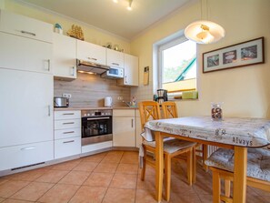 A compact kitchen with white cabinets, a built-in oven, a microwave, and a window providing natural light.