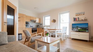 En modern lägenhet med vardagsrum, matplats, kök och en TV.
