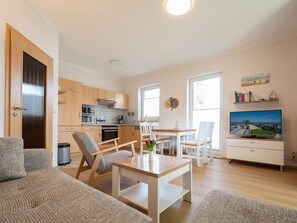 Eine moderne Wohnung mit Wohnzimmer, Essbereich, Küche und Fernseher.