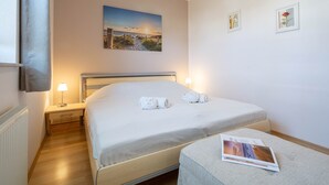 Ett välordnat sovrum med en säng, sänglampor, ett litet sängbord och en tavla som hänger på väggen.