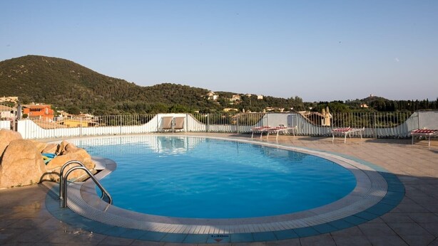 A swimming pool with a surrounding fence, lounge chairs, and a mountainous backdrop. - Vacation Home "Sobìa Manna" with Mountain View, A/C, Pool, Garden & Grill (CHIA)
