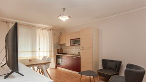 A modern kitchen with a dining area, a flat-screen TV, and two armchairs. - Vacation Home "Sobìa Manna" with Mountain View, A/C, Pool, Garden & Grill (CHIA)