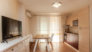 A modern kitchen with a TV, dining table, chairs, and cabinets. - Vacation Home "Sobìa Manna" with Mountain View, A/C, Pool, Garden & Grill (CHIA)