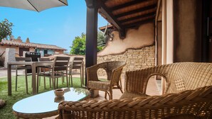 An outdoor patio with wicker furniture, a glass table, and a stone wall. - Vacation Home "Sobìa Manna" with Mountain View, A/C, Pool, Garden & Grill (CHIA)