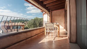 Un balcón con vistas a un paisaje montañoso, techo de madera y una mesa con sillas.