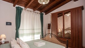 Un dormitorio con cama, cortinas, mesita de noche, lámpara y armario.