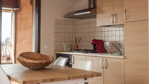 Una cocina moderna con gabinetes de madera, una campana extractora de acero inoxidable y una cafetera roja.