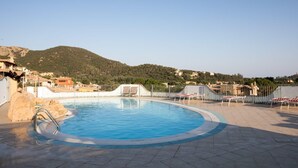 Una piscina con sillones de descanso, una escalera metálica y vistas a un paisaje montañoso.