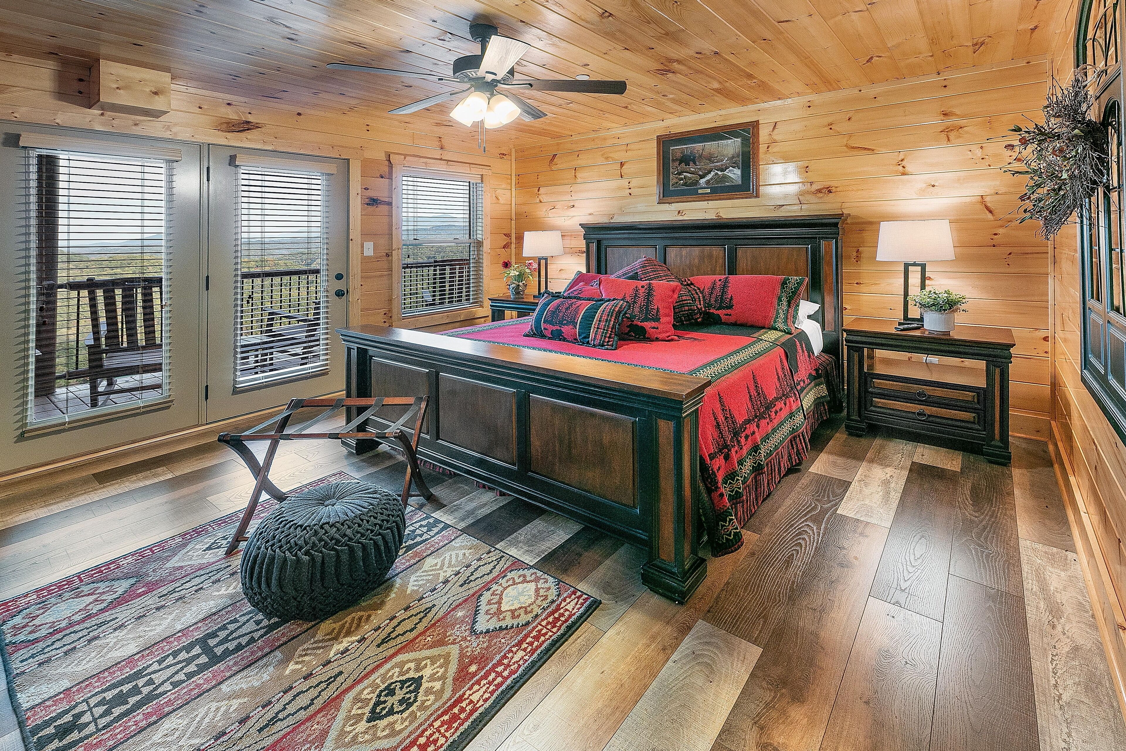 A log cabin bedroom with a bed, a nightstand, a chair, a window with blinds, and a ceiling fan.