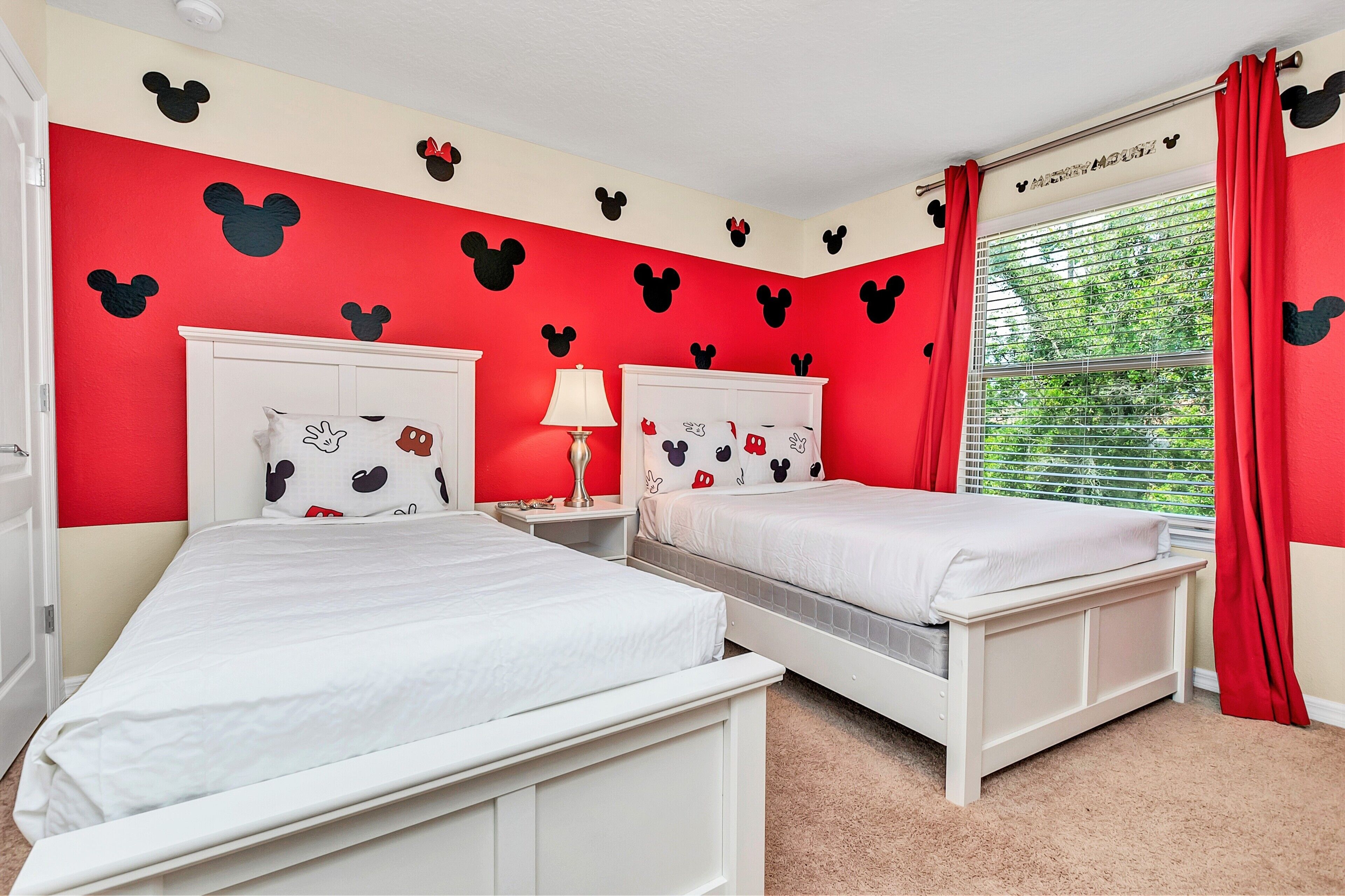 Camera da letto con due letti, pareti rosse e decorazioni con Topolino.