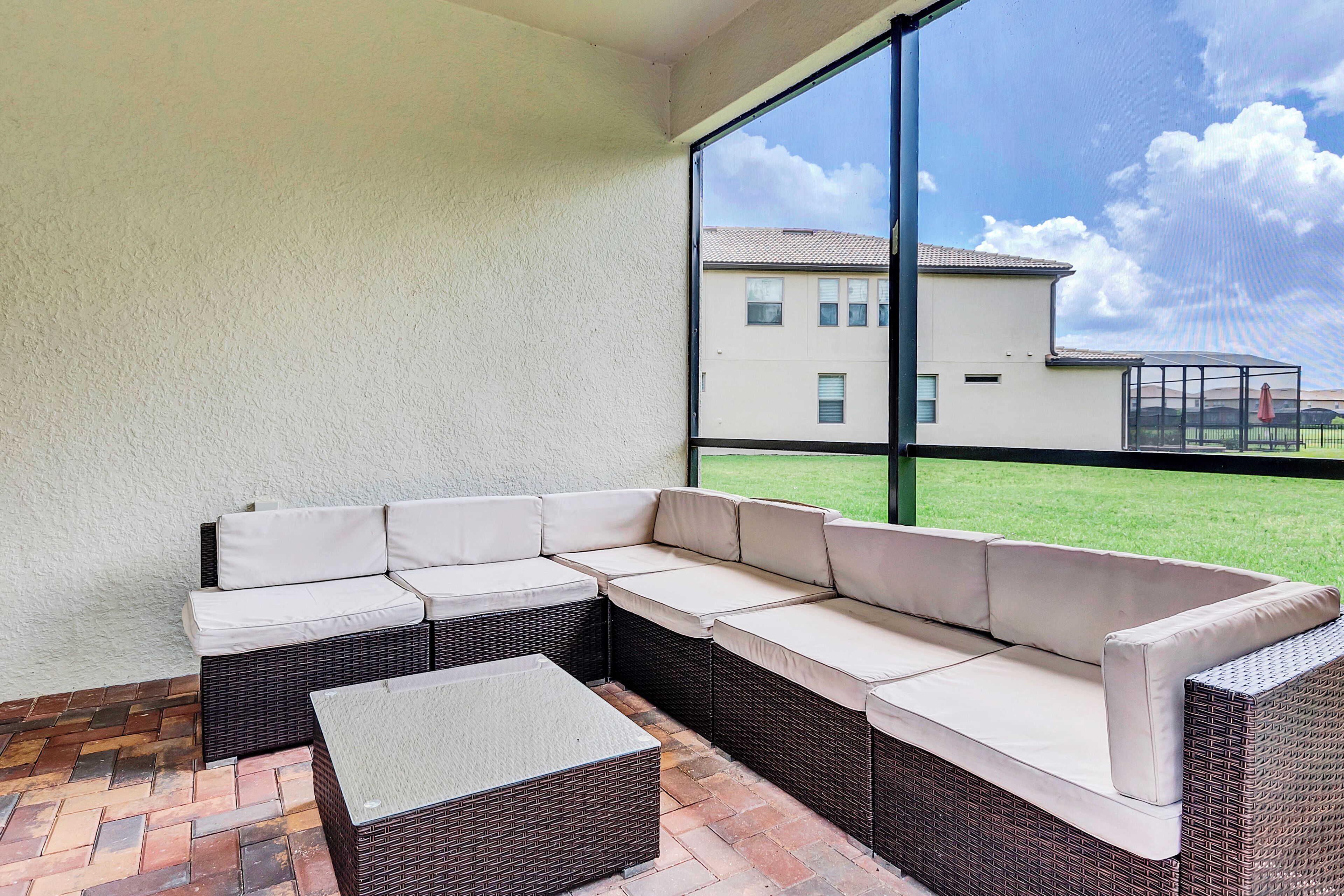 A covered patio area with a sectional sofa and a small table.