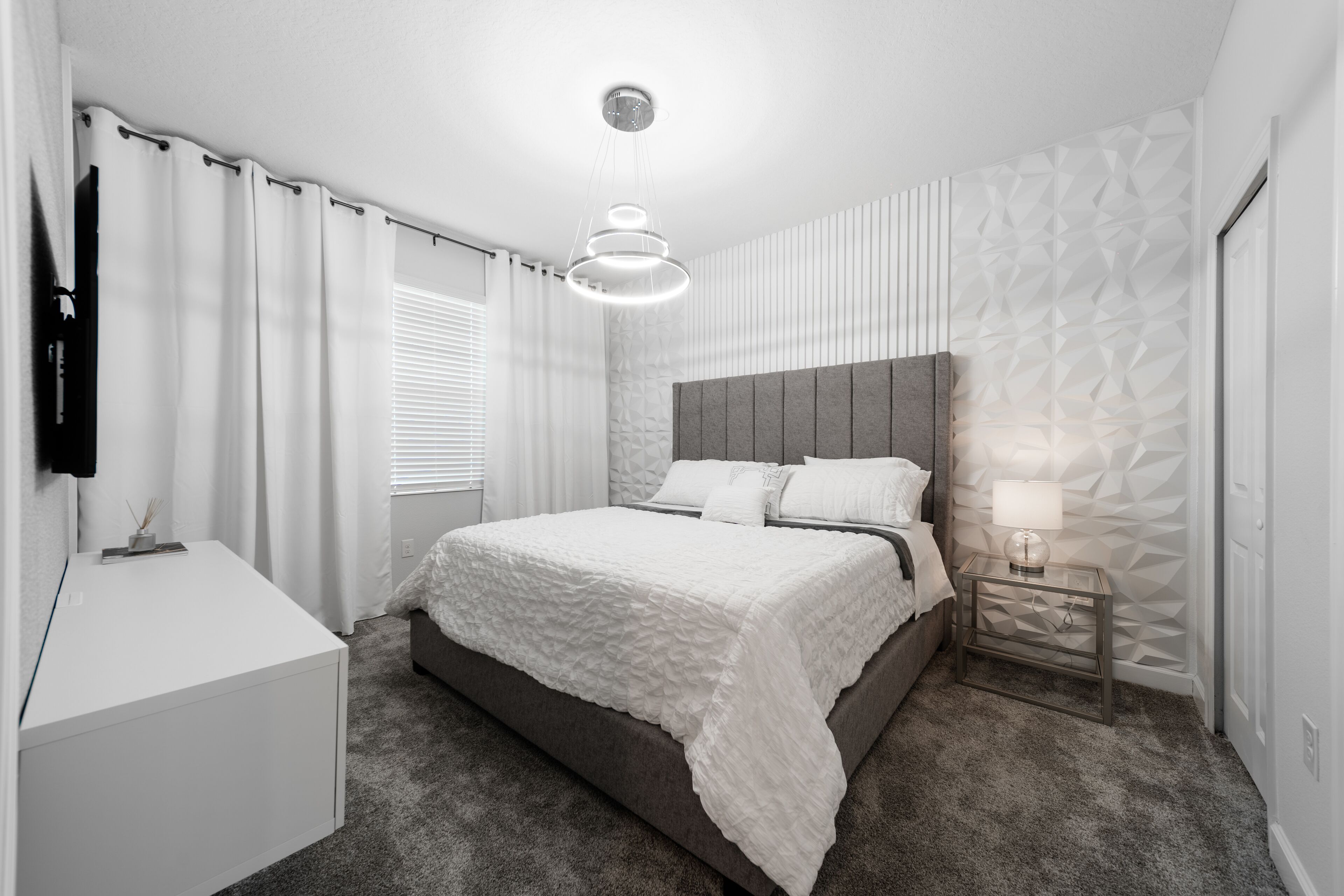 Un dormitorio moderno con una cama grande, una mesita de noche con lámpara y un armario.