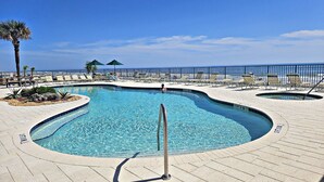 A pool area with a clear blue pool, lounge chairs, and a palm tree. - Oceanfront 1BR | Balcony | Steps to Sunglow Pier | Free Daily Activities Included (Daytona Beach Shores)