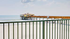 A beach with a wooden pier extending into the ocean, a building on the pier, and a clear sky. - Oceanfront 1BR | Balcony | Steps to Sunglow Pier | Free Daily Activities Included (Daytona Beach Shores)