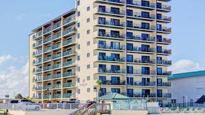 A multi-story hotel with balconies, a swimming pool, and a covered area. - Oceanfront 1BR | Balcony | Steps to Sunglow Pier | Free Daily Activities Included (Daytona Beach Shores)