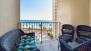 A balcony with wicker furniture and a view of the beach.