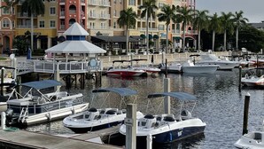 Marina con varias embarcaciones amarradas, un edificio frente al agua con balcones, y una zona cubierta con un letrero que dice "CABANA".
