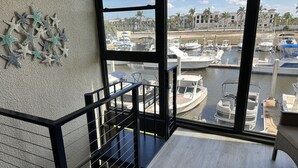 Un balcón con vista a un puerto deportivo, mostrando barcos amarrados y un edificio al fondo.