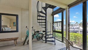 Un interior moderno con una escalera de caracol, un ventanal con vista a barcos y un banco.