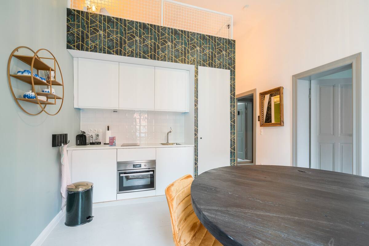 A modern kitchen with white cabinets, a black countertop, and a round dining table.