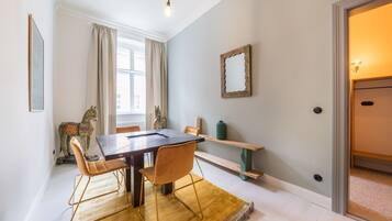 A dining area with a wooden table, two chairs, a yellow rug, a horse sculpture, and a mirror on the wall.
