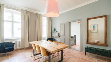 A dining area with a wooden table and chairs, a hanging light fixture, a bench, and a large mirror on the wall.