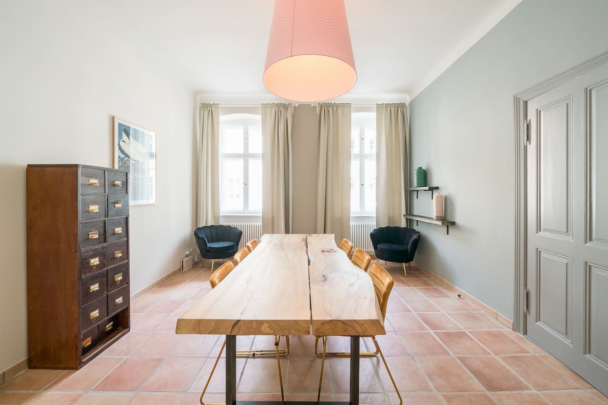 A conference room with a long wooden table, chairs, a cabinet, and a hanging light fixture.