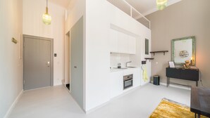 Eine moderne Küche mit weißen Schränken, einem eingebauten Ofen und einer schwarzen Arbeitsplatte. Es gibt ein kleines Spülbecken und einen Spiegel über der Arbeitsplatte.
