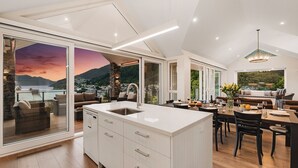 Een moderne keuken met een groot eiland, een eetgedeelte met uitzicht en een gezellige zithoek met uitzicht op de bergen.