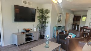 Ein modernes Wohnzimmer mit Flachbildfernseher, Couchtisch, Sofa und Essbereich.